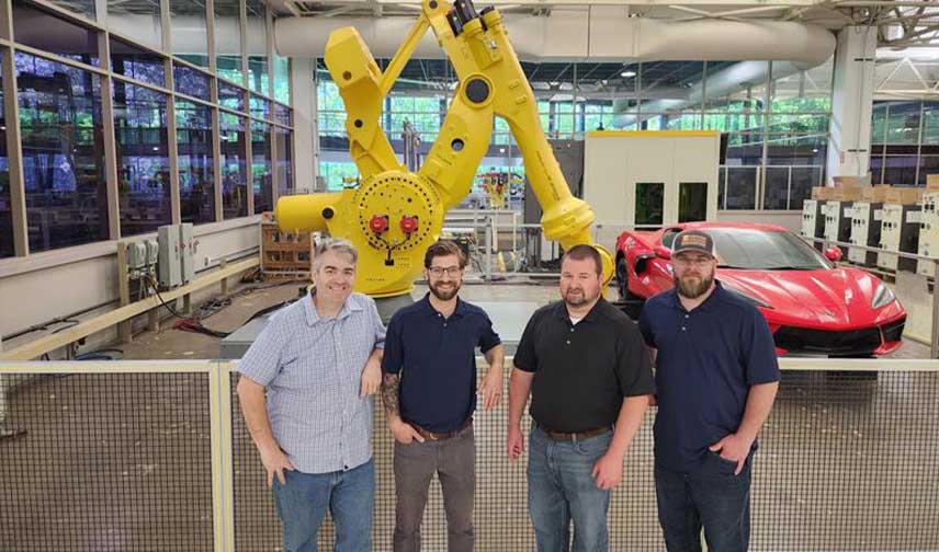 Invent Automation Team in Front of a Yellow Machine